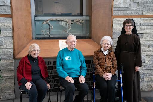 Ted Thompson with his wife Rita, Sister Damien Savino, and Sister Aquinas in front of the Oreodont skeleton displayed in Albertus Magnus Hall