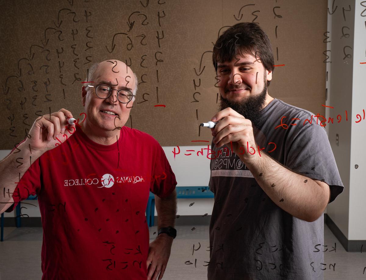 梅哈诺维奇和斯宾塞拿着记号笔，对着一块写满数字的透明玻璃板